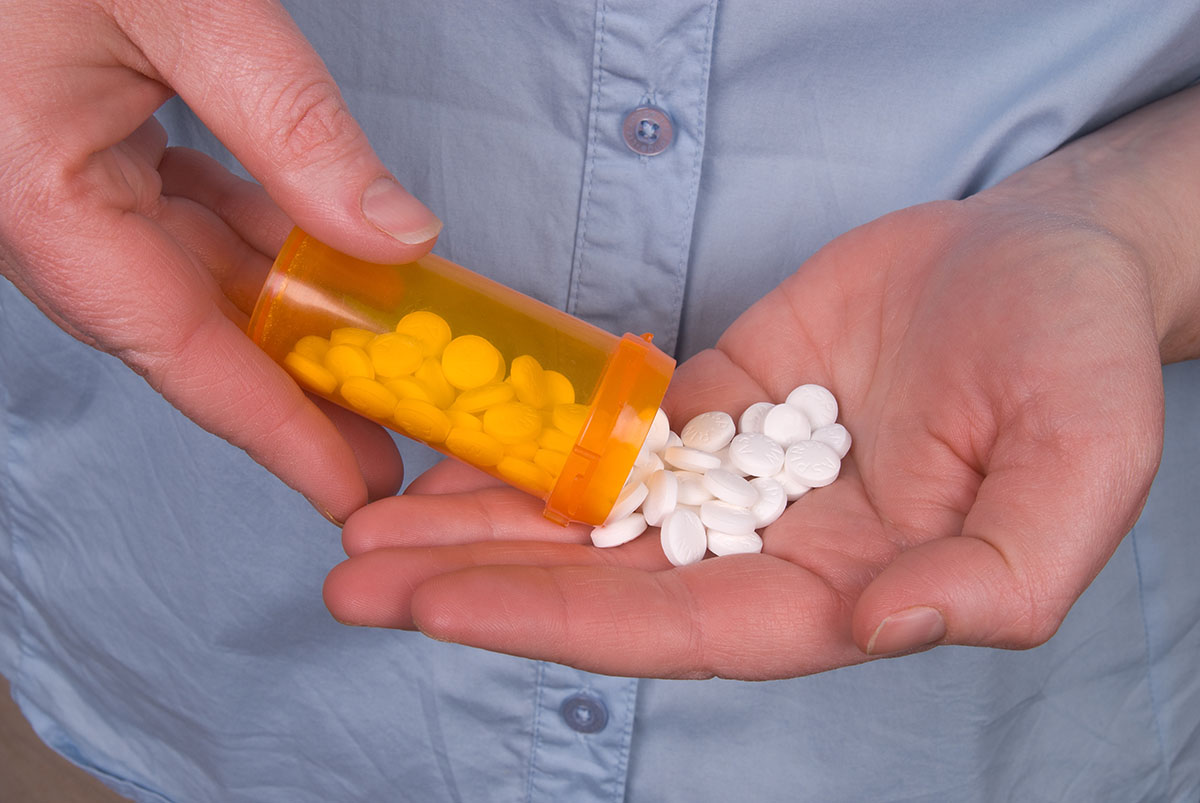 a man pours pills into his hand and thinks about the utah opiate abuse