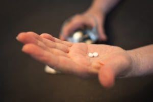 A man stares at two small white pills and wonders if he should enter an opioid addiction treatment program in UT