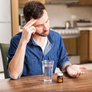 A man stares at a pile of pills in his hand and wonders if he should enter an oxycodone addiction treatment program in UT