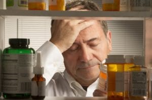 A man stares at an empty bottle of prescription drugs and wonders about prescription drug addiction facts. 