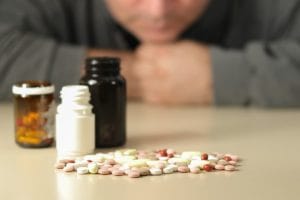 A person stares at a pile of pills and wonders if they need help from substance abuse treatment programs