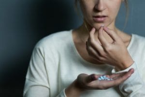 woman taking Xanax from handful of pills without knowing Xanax addiction facts