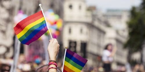 People at an LGBT parade waver flags as they wonder why LGBT have a higher addiction risk