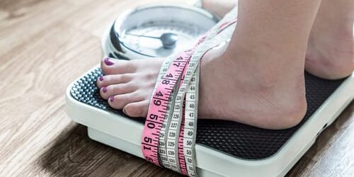 A woman is chained to the scale by tape measures and the 3 myths about eating disorders