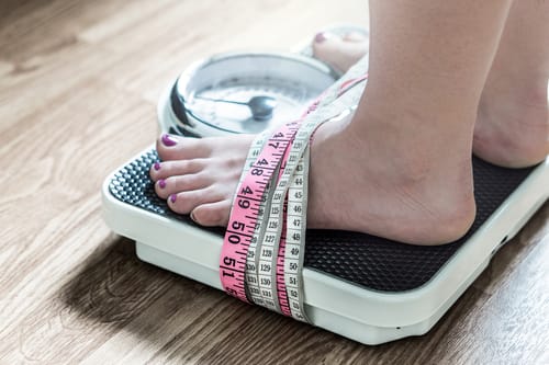 A woman is chained to the scale by tape measures and the 3 myths about eating disorders