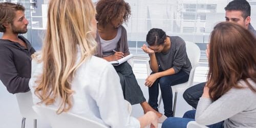 A group of people comfort a woman as she wonders why she's depressed even though she's in recovery