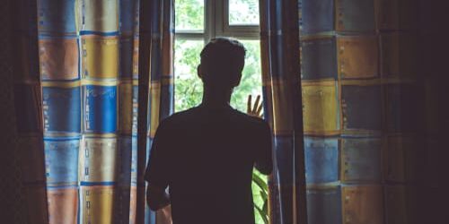 A man presses his hand against a window and tries to think of 4 ways to take the edge off of opioid withdrawal