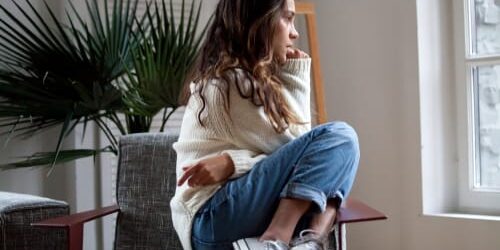 989 A woman sits curled up in a chair and wonders can mental illness shorten your life