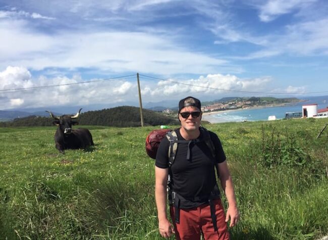 a man stands next to a cow and thinks about cow pies and boundaries
