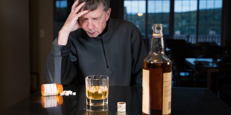 baby-boomers-and-substance-abuse an older man looks at pills and alcohol as he considers baby boomers and substance abuse