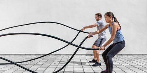 A man and woman exercise with large cables as a part of making time for self-care