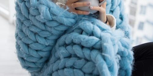 A woman wraps herself in a blanket and drinks hot cocoa as she thinks about 4 winter challenges for people recovering from addiction