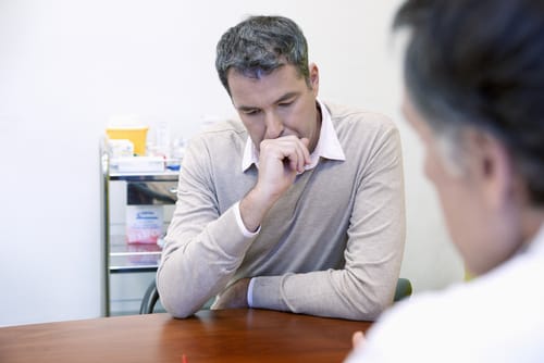 A man talks to his doctor about the difference between medication assisted treatment and drug replacement therapy