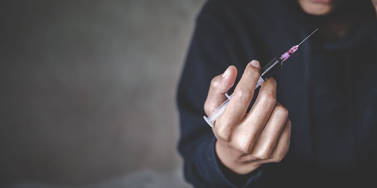 A person holds a needle, and wonders how addictive is heroin