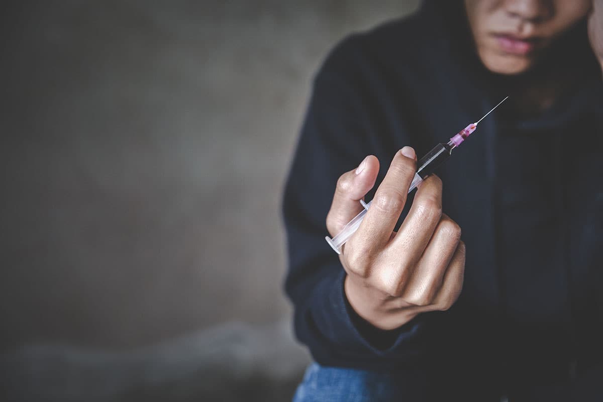 A person holds a needle, and wonders how addictive is heroin