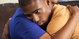 A mother hugs her son after they talk about 3 ways her PTSD can affect her child