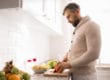 A man begins chopping vegetables as he thinks about what to eat early in recovery