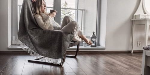 A woman sits in a chair with a cup of tea and wonders if bipolar disorder is different in men and women