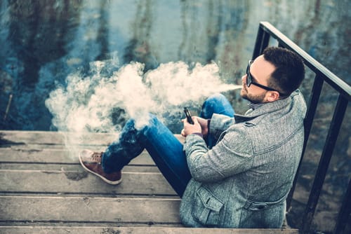 shutterstock_399082465 a man vapes and wonders is vaping ok during addiction recovery