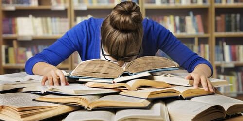 a woman puts her head down on a pile of books that explain why language matters when discussing addiction