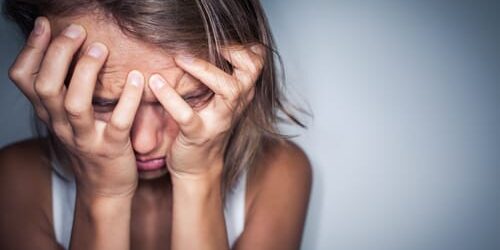 a woman covers her face and wonders do you know the signs of an anxiety disorder