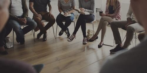 a group of people listen to someone ask why should i go to meetings