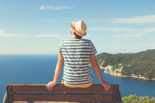 a man sits on a bench and looks out to sea as he thinks about misconceptions about depression.
