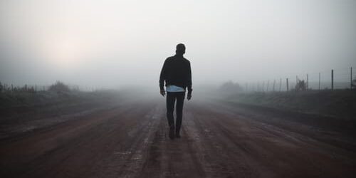 a man walks down a foggy road as a way of confronting the past