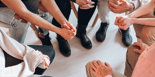 shutterstock_675117181 a group of people talk about 5 benefits of group therapy