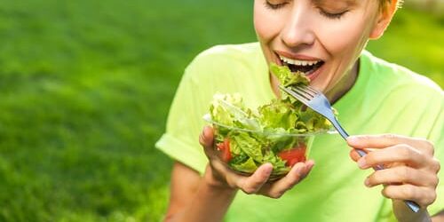 shutterstock_790584787 a woman eats a salad after she remembers ways that a healthy diet supports addiction recovery