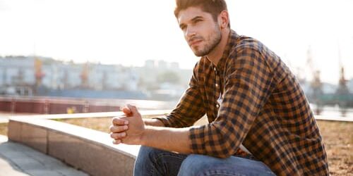 wr35467i A man sits on a low stone wall and wonders if you ever completely recover from addiction