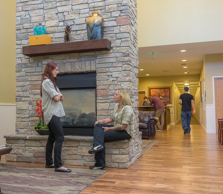 women talking in front of a fireplace