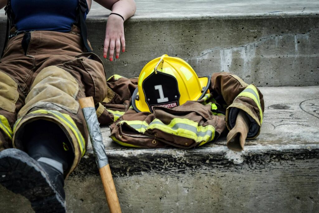 A firefighter sitting next to her uniform jacket and helmet