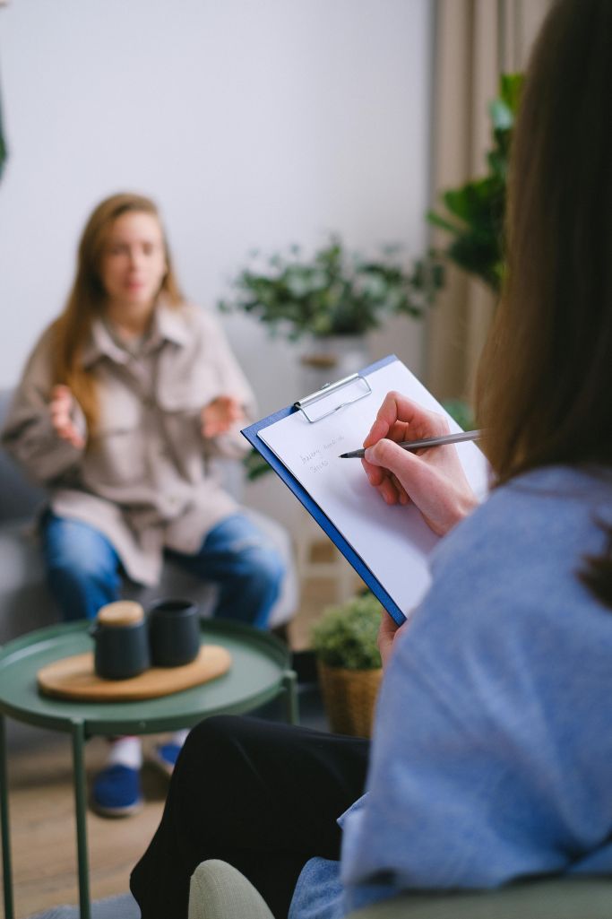 A counseling writing on a clipboard in a session