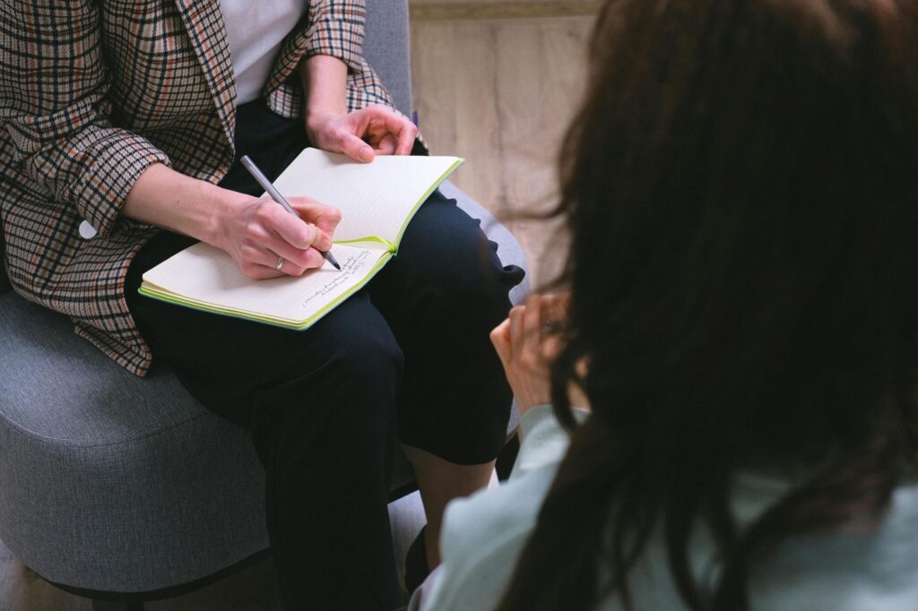 A counselor writing in her notebook during a session with a patient