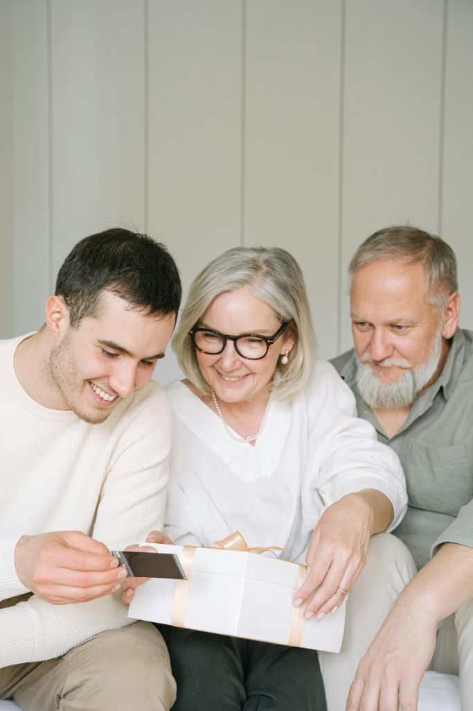 A mother and father looking at photos with their adult son