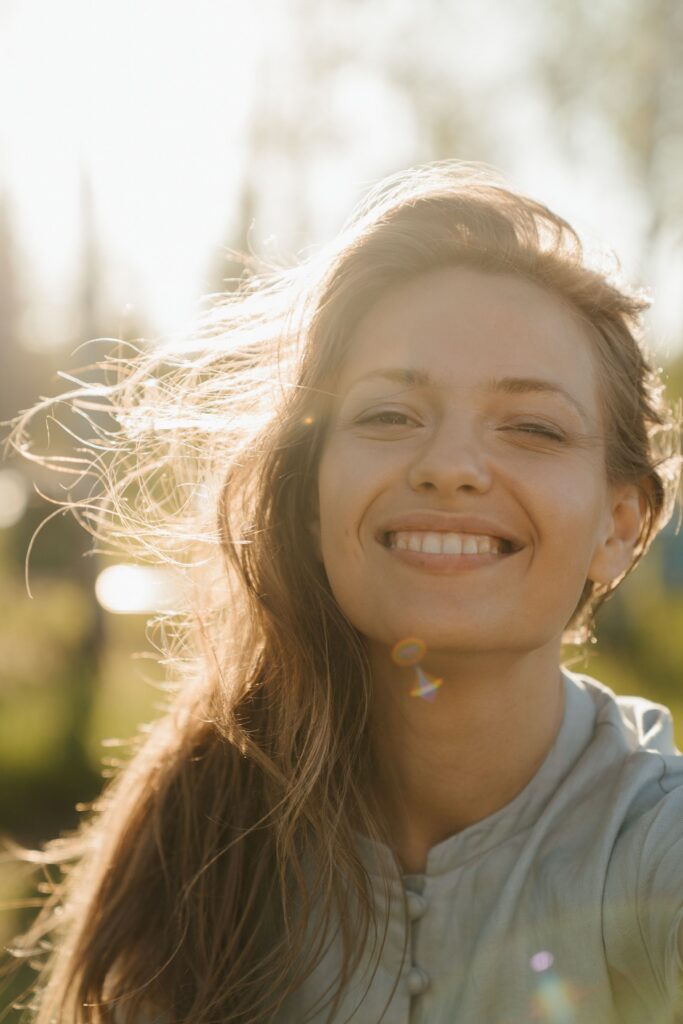 woman smiling with sun shining behind her